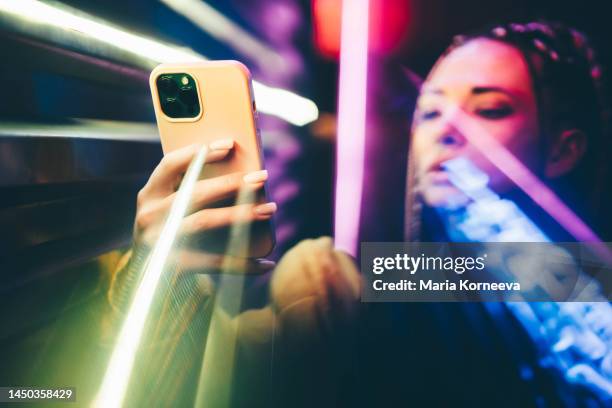 woman using mobile phone in neon lights. - e commerce innovation stock pictures, royalty-free photos & images