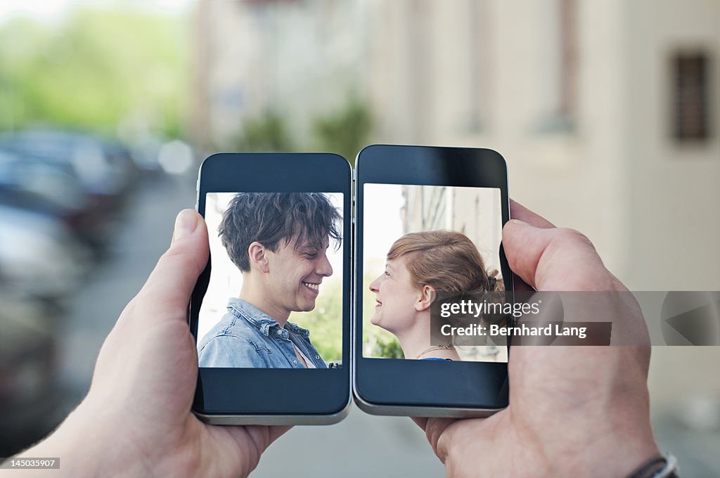 Young couple communicating via two smartphones