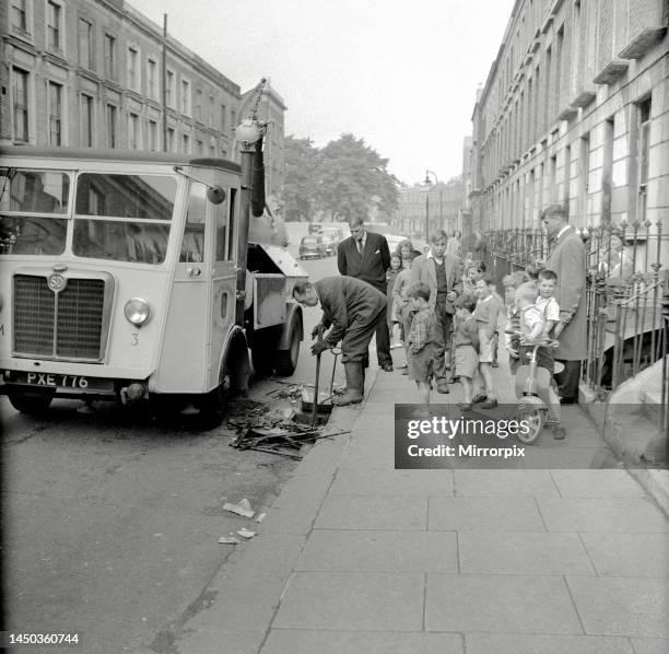 Children watch in the streets as two detectives oversee the clearing of the drains in Edenham Street - they were looking for the murder weapon...