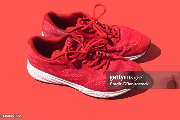 used red running shoes on a red background. concept of exercise, marathon, race, healthy life, training and comfort. - sapato de lona imagens e fotografias de stock