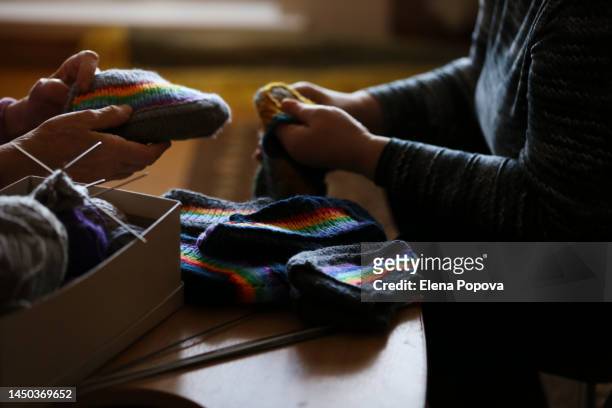 cropped hands elderly woman and her caregiver holding colorful rainbow knitted socks - unwanted present stock pictures, royalty-free photos & images