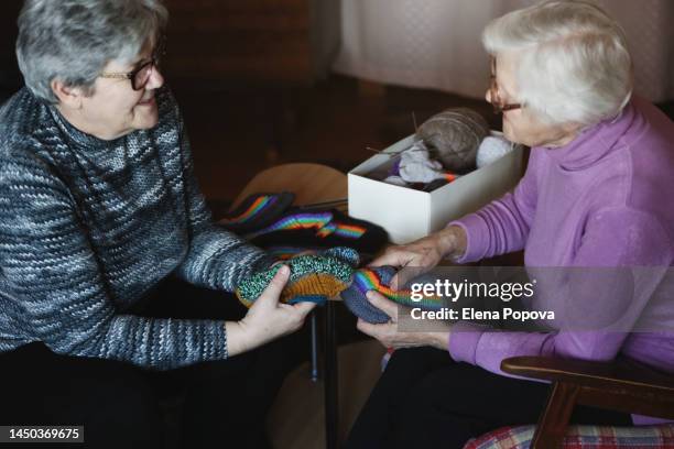 elderly woman knitting colorful rainbow socks and showing hobbies works for caregiver - arcas stock pictures, royalty-free photos & images