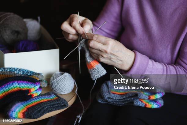 midsection elderly woman knitting colorful woolen socks at home - arcas stock pictures, royalty-free photos & images