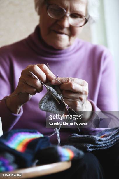 elderly woman knitting grey woolen socks at home, selective focus - arcas stock pictures, royalty-free photos & images