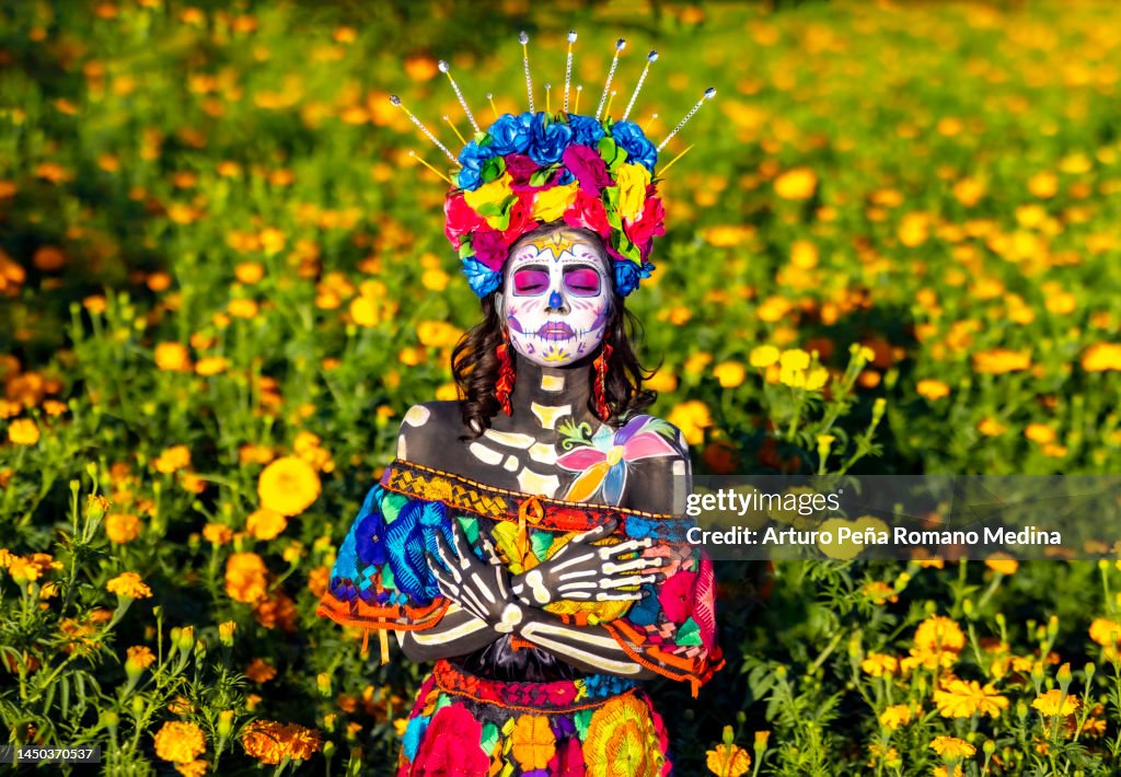 Catrina in a field of cempasúchil flowers enjoying the sun's rays