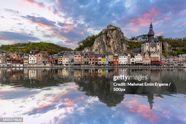 scenic view of lake by buildings against sky during sunset,dinant,belgium - namur stock-fotos und bilder