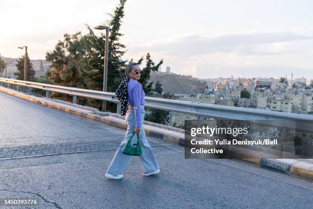 woman walking across the road outside - middle east cool stock pictures, royalty-free photos & images