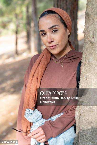 woman standing outside in the trees looking serious - middle east cool stock-fotos und bilder