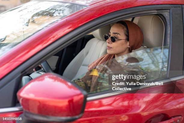 woman sitting behind a steering wheel of a vehicle - arab woman driving stock pictures, royalty-free photos & images