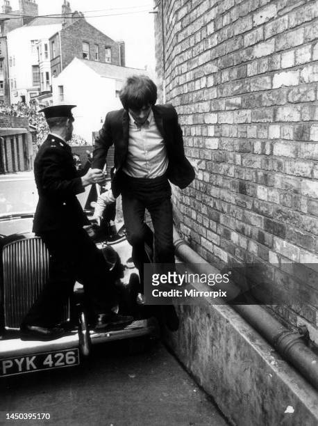 George Harrison is the last of the Beatles to jump over the car and run into the Futurist Theatre Scarborough. They did this to avoid the waiting...