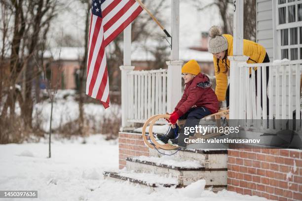 happy excited little boy in warm clothes, having fun riding sled with his bigger sister on the snow outdoors on a sunny winter day.  active, leisure, holidays - happy holidays family stock pictures, royalty-free photos & images