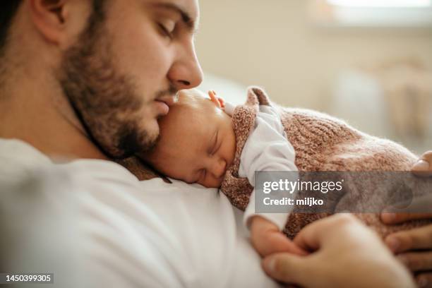 newborn baby sleeping in her father's arms - father holding sleeping baby imagens e fotografias de stock