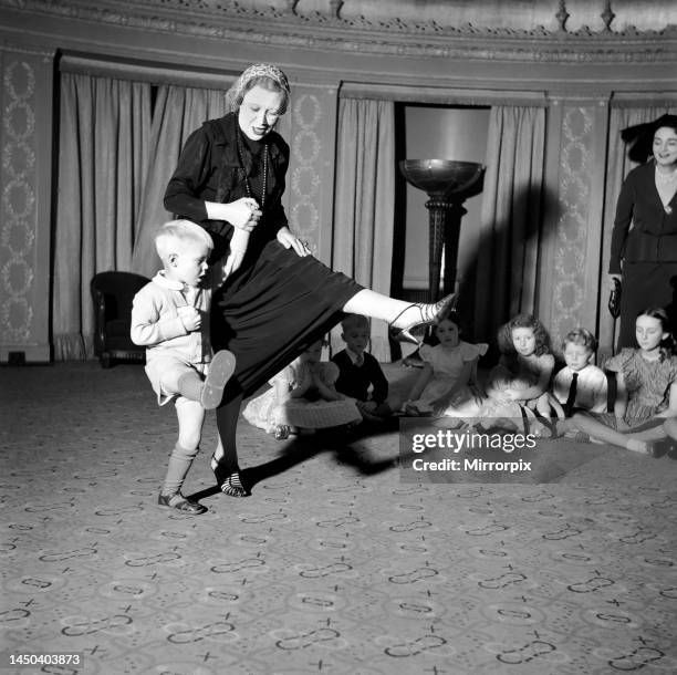 Ruby Miller, one of the ex-Gaiety Girls, who was attending the 32nd Actresses Gaiety Party at the Dorchester shows Michael Grieves, aged three, how...