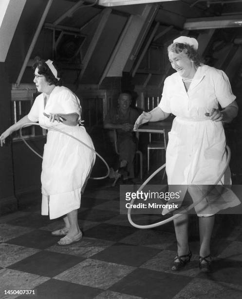 Two canteen workers exercise with 'hula' hoops. 30th September 1958.