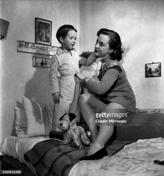 Mother caring for her son, seen here putting him to bed. December 1952.