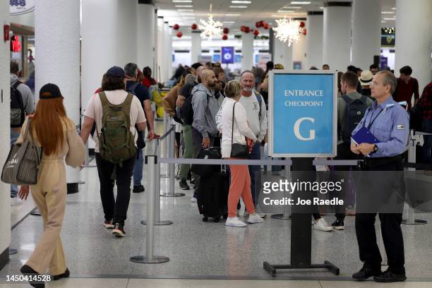 Travelers stand in line for a TSA checkpoint at the Miami International Airport on December 19, 2022 in Miami, Florida. Miami International Airport...