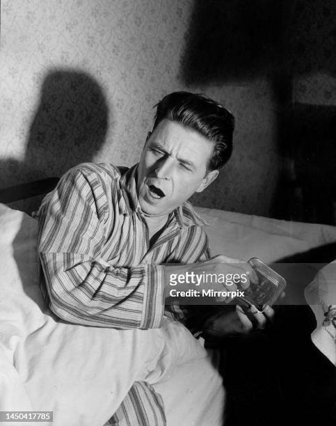 Sleepy man. A man wakes up, yawning, turns off his alarm clock. December 1952.