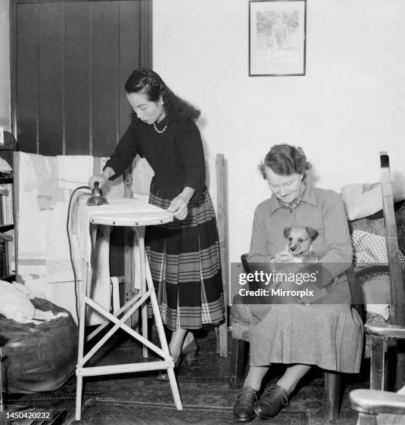 Woman ironing in the living room of her home February 1953.