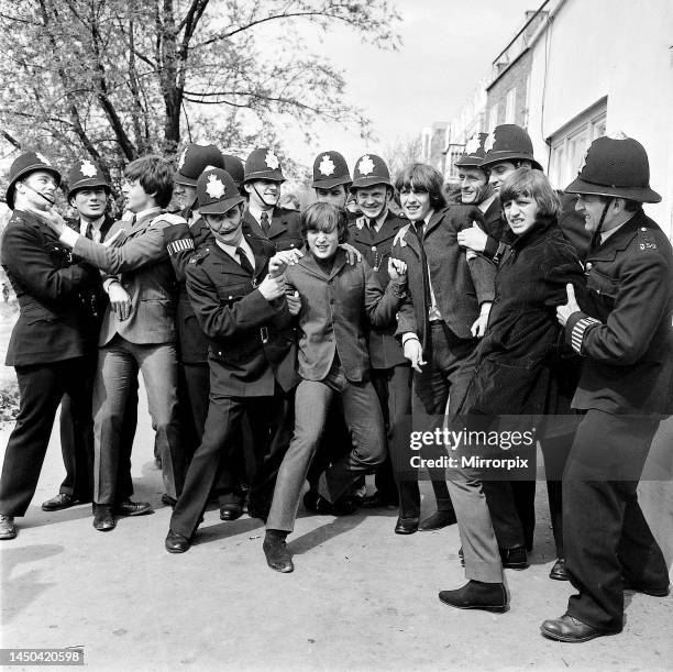 The Beatles in the strong arm of the law while filming Help!, outside The City Barge pub, Chiswick, London, 24 April 1965. Beatles members left to...