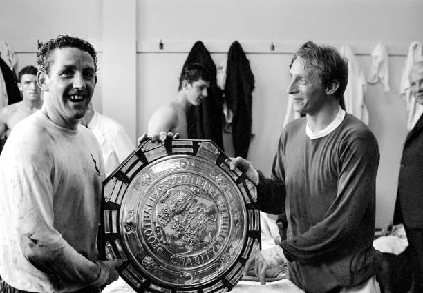 Manchester United versus Tottenham Hotspur. Dennis Law and Dave MacKay hold the FA Charity Shield in the dressing room after the match. August 1967.