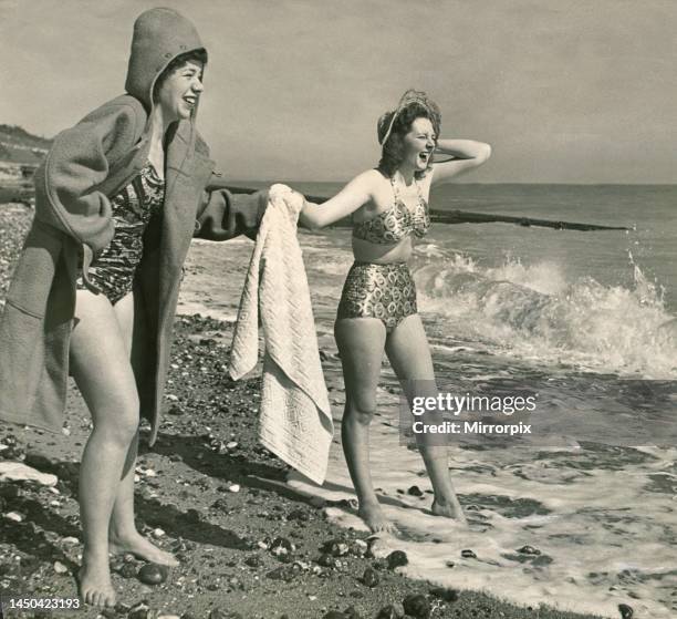 Two women - Barbara Howes and Sylvia Hansen came in duffle coats over their bathing costumes as they paddle in the sea. March 1948.