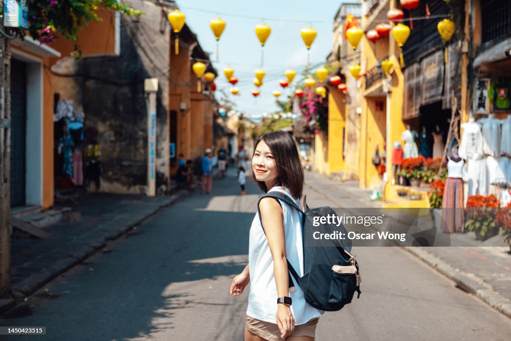 Smiling young female Asian solo traveler with backpack traveling in Vietnam