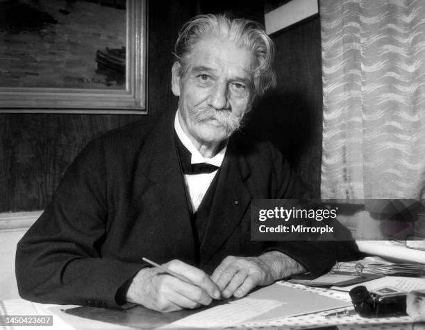 Dr. Albert Schweitzer sitting at desk writing letter October 1955.