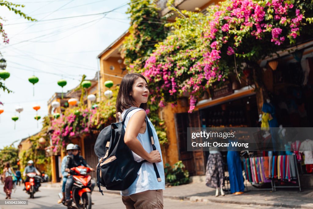 Low angle view of young female Asian solo traveler with backpack traveling in Vietnam
