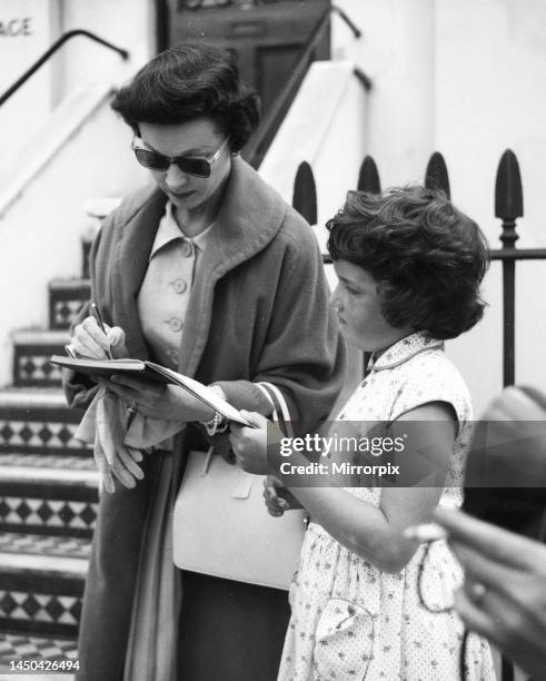 Actress Vivien Leigh signing autographs for a young fan in London, August 1956.