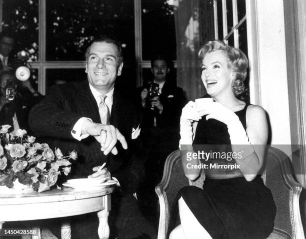 American film star Marilyn Monroe drinking a cup of tea as she sits next to British thespian actor Laurence Olivier at a press conference at the...