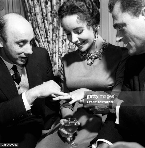 Elizabeth Taylor with her husband American producer Mike Todd, showing off her diamond ring to Mirror writer Donald Zec. April 1957.