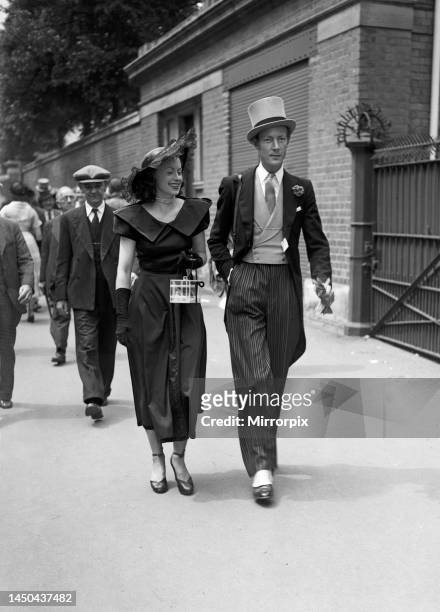 Two racegoers walk down the street to the races. Ascot, June 1949.