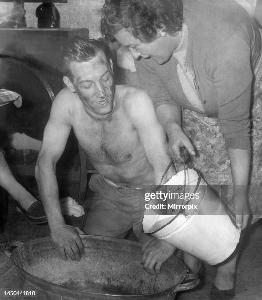 Miner, Mr Allan Hedley, washes in a tin bath with water boiled on the only fire in the house by his landlady, Mrs Alice Lawson.