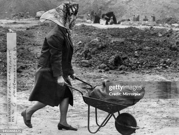 Woman wheeling a wheelbarrow filled with a sack of coal at Bentley Lane in Walsall, Staffordshire. April 1968.