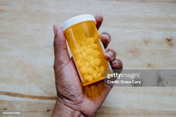 woman holds bottle of prescription medication - frasco de comprimidos imagens e fotografias de stock