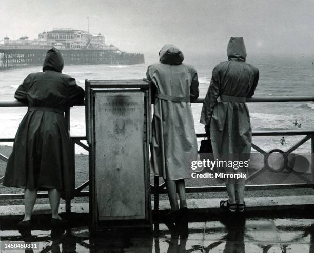 Bank Holiday brought a break in the sunny weather of recent weeks Three girls in raincoats watch members of the Brighton Swimming Club having a...