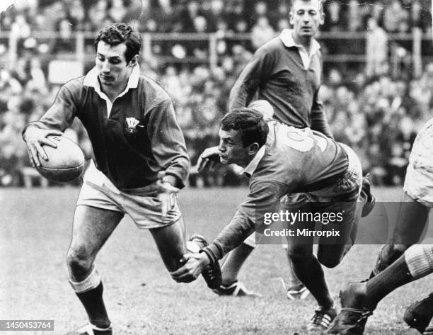 Referee Mike Titcomb watches as the Irish scrum-half Roger Young tries to catch Welsh scrum-half Gareth Edwards as he breaks from behind the scrum.