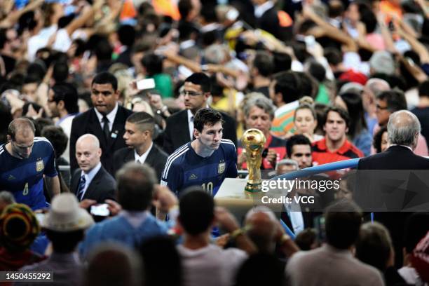 Lionel Messi of Argentina looks at the World Cup trophy after the 2014 FIFA World Cup Brazil Final match between Germany and Argentina at Estadio...
