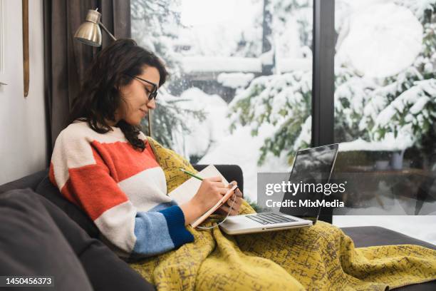 young woman studying for the exam and warming under the blanket - cosy winter stock pictures, royalty-free photos & images