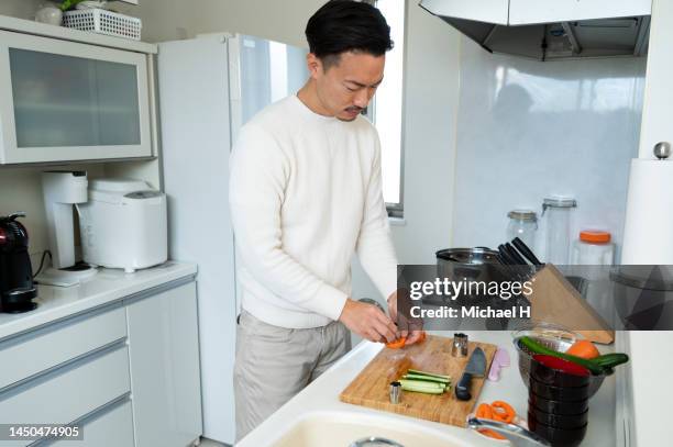 young man tasting food while cooking in the kitchen. - japanese fat man bildbanksfoton och bilder