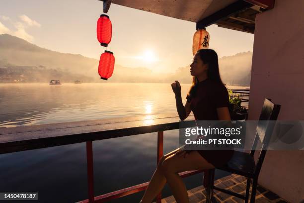 a woman sits by a misty river, villages and mountains, and the sun shines. ban rak thai, yunnan china, mae hong son, thailand. - provincia de mae hong son fotografías e imágenes de stock