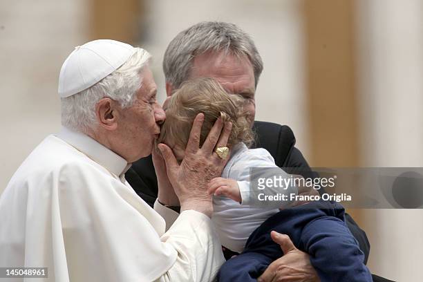 Pope Benedict XVI, flanked by his personal secretary Georg Ganswein, kisses a baby during his weekly audience in St. Peter's Square on May 23, 2012...