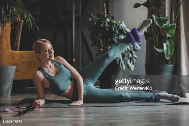 smiling woman exercising with ankle weights on exercise mat at home - ankle weights stock pictures, royalty-free photos & images