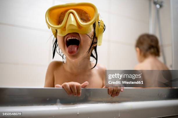 boy wearing swimming goggles taking bath in bathroom - brothers bathroom stock-fotos und bilder