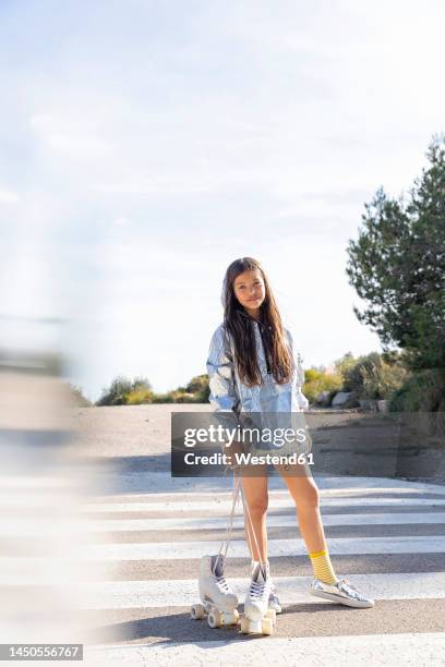 girl holding white roller skate on zebra crossing - road signal ストックフォトと��画像