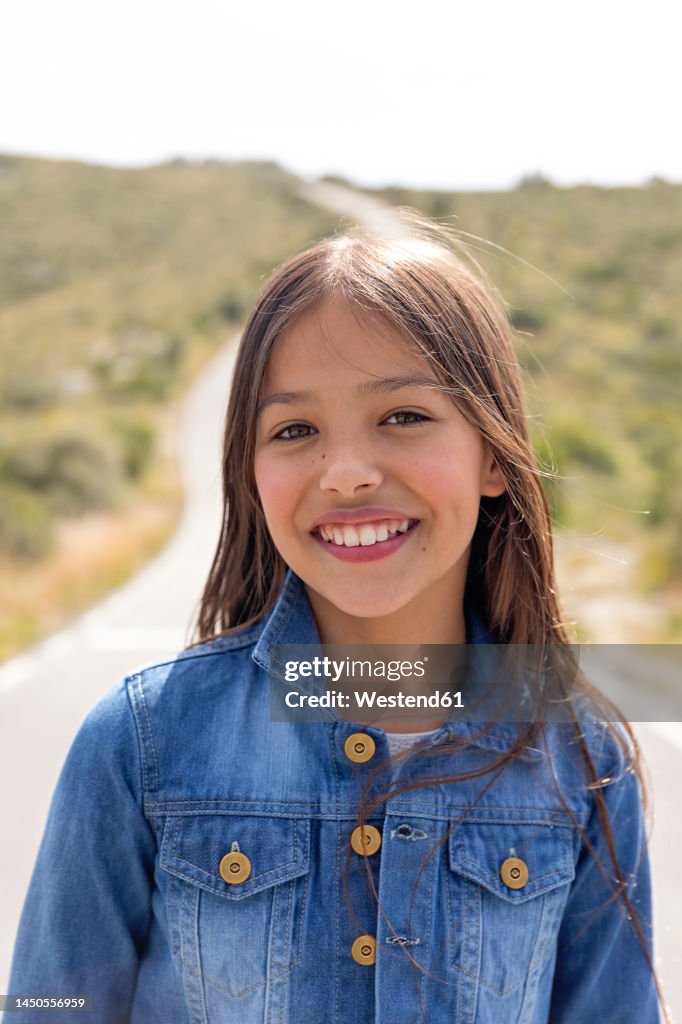 Smiling girl in denim jacket on road