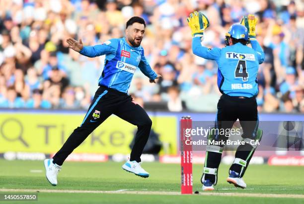 Rashid Khan of the Strikers celebrates the wicket of Matthew Gilkes of the Thunder with Harry Nielsen of the Strikers during the Men's Big Bash...