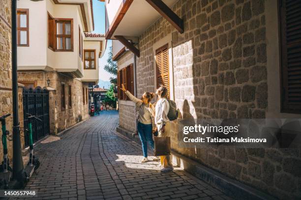 two young women with backpacks walk in old city. - stadt antalya stock-fotos und bilder