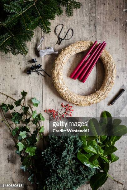 preparation of christmas wreath made of spruce, juniper, ivy, rose hips and candles - flower garland stock pictures, royalty-free photos & images