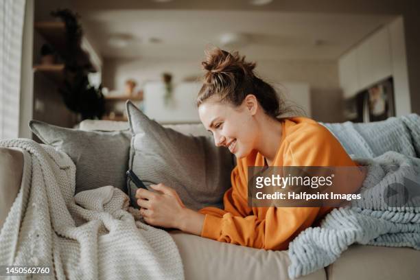 young woman resting on sofa with smartphone. - blanket photos et images de collection